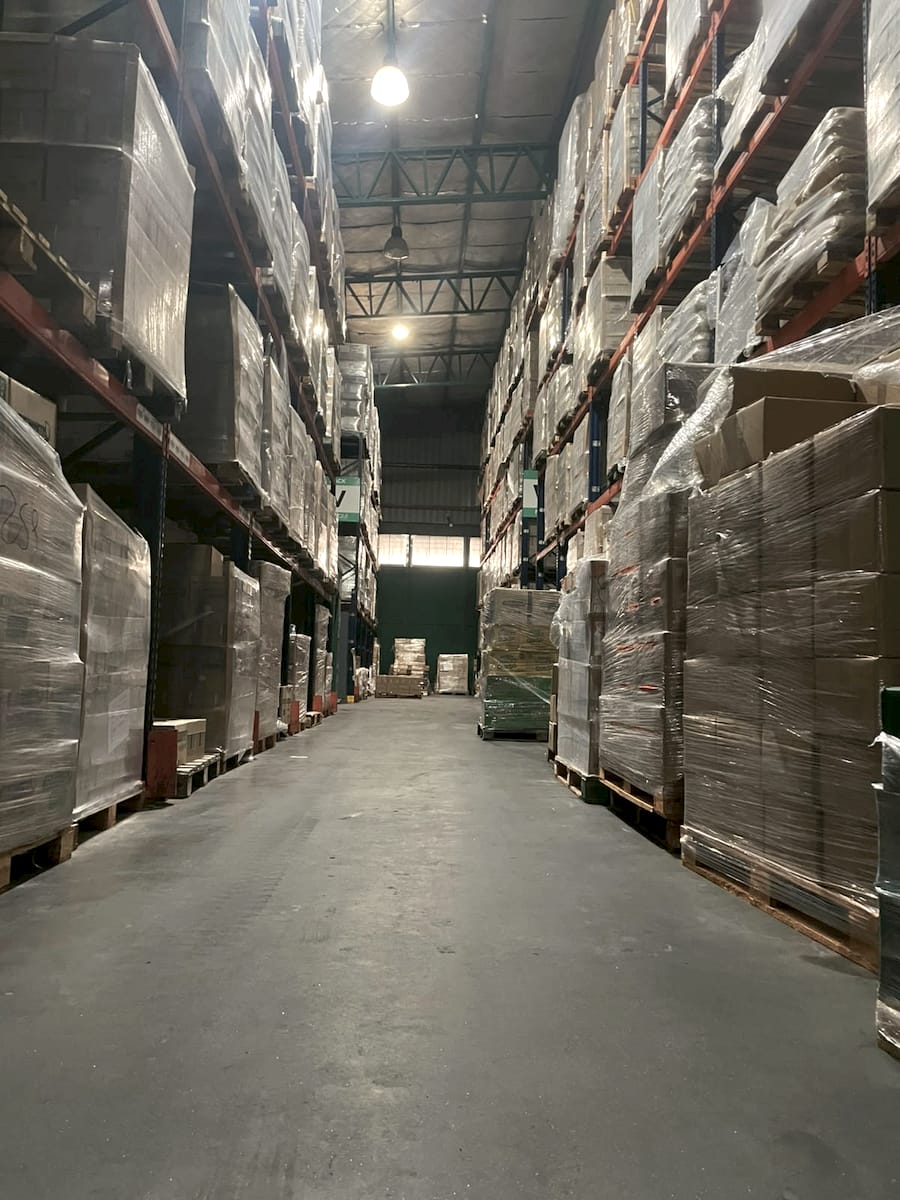 Pasillo del depósito de Tratenfu con estanterías altas y mercadería lista para distribuir